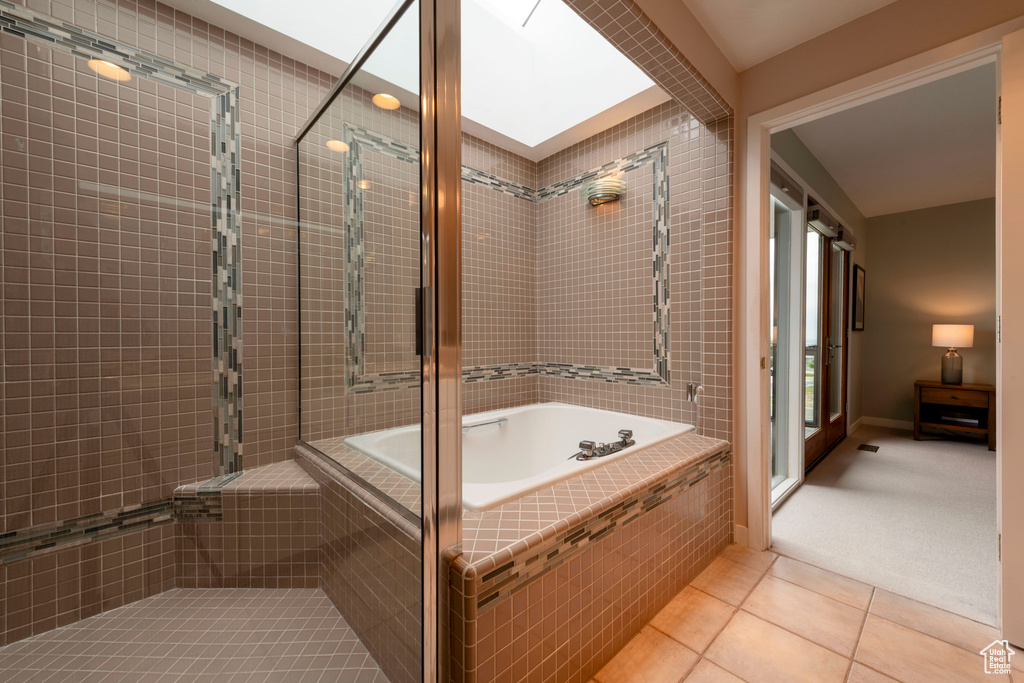 Bathroom with tile patterned flooring, a relaxing tiled tub, and tiled shower