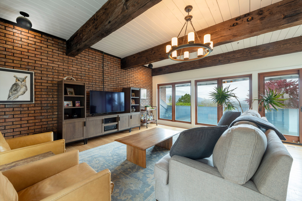 Living room featuring brick wall, a chandelier, wood finished floors, and beamed ceiling