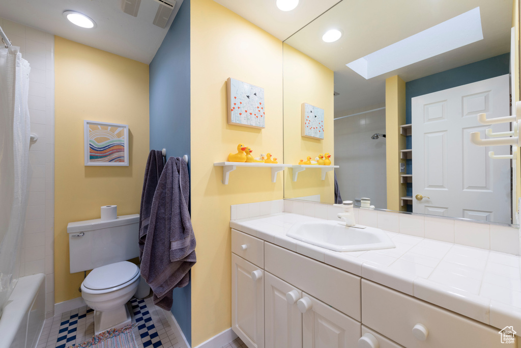 Full bathroom featuring toilet, baseboards, vanity, a skylight, and recessed lighting