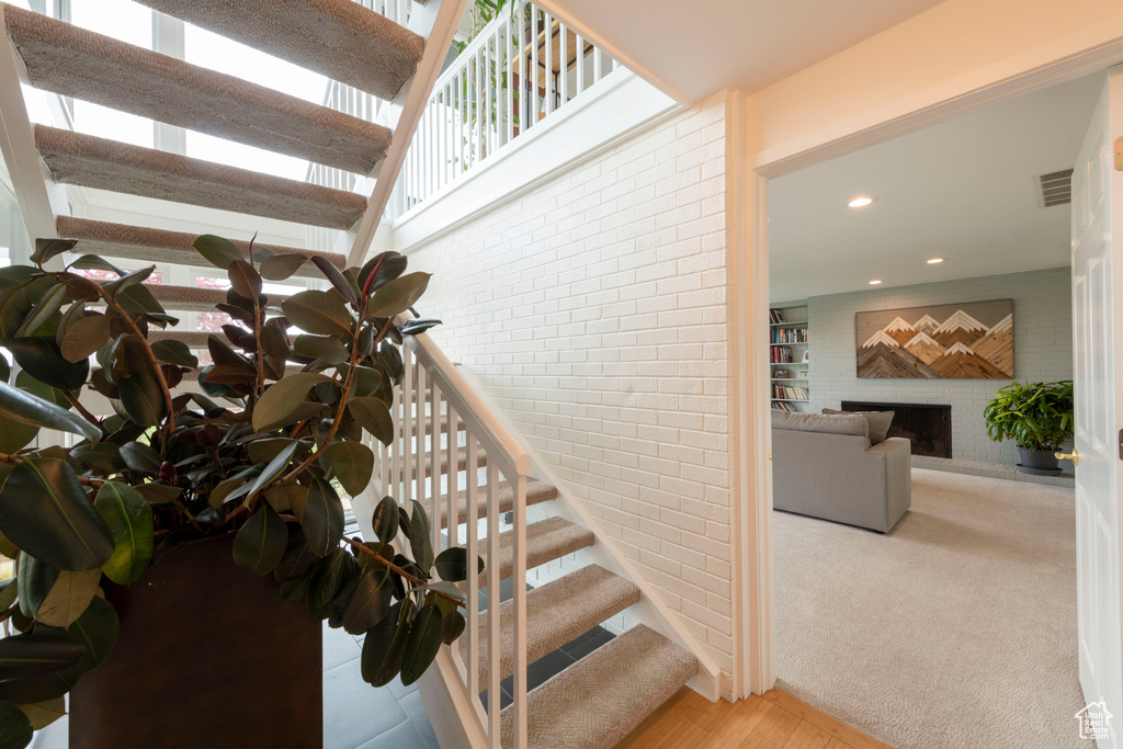Stairway with brick wall, recessed lighting, a brick fireplace, and plenty of natural light