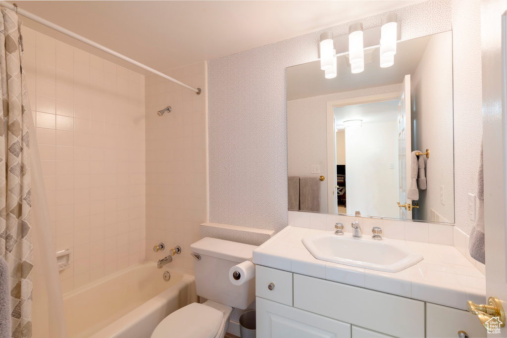Bathroom with toilet, shower / bath combination with curtain, and vanity