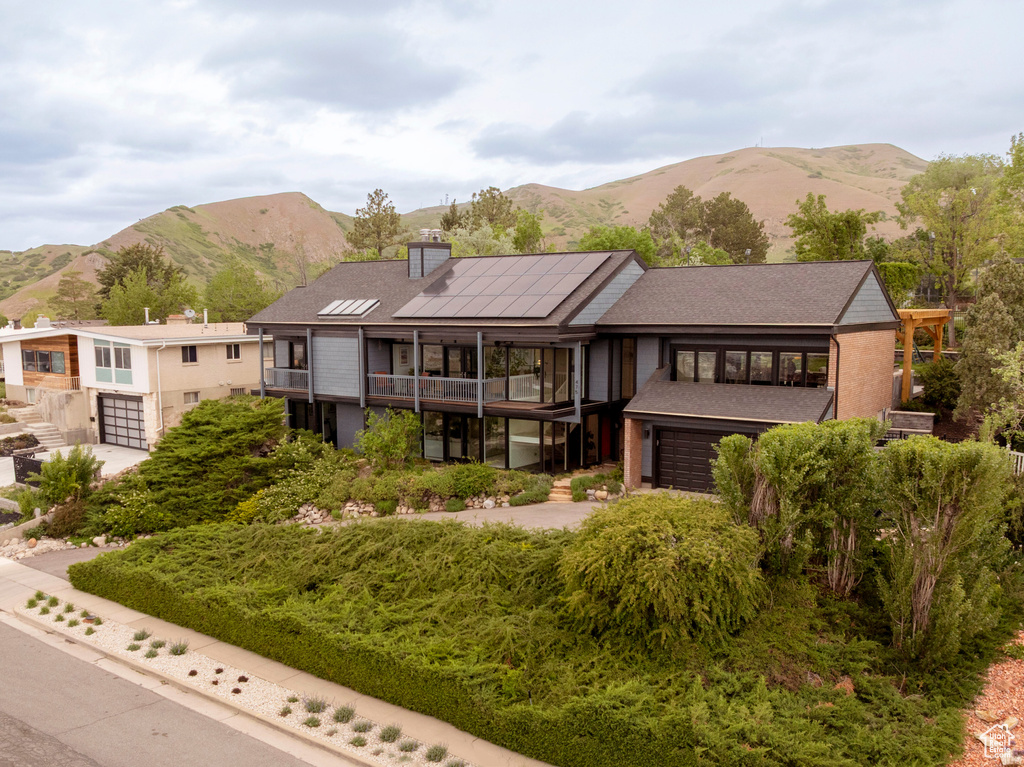 View of front of house featuring a balcony, a garage, a mountain view, and a chimney