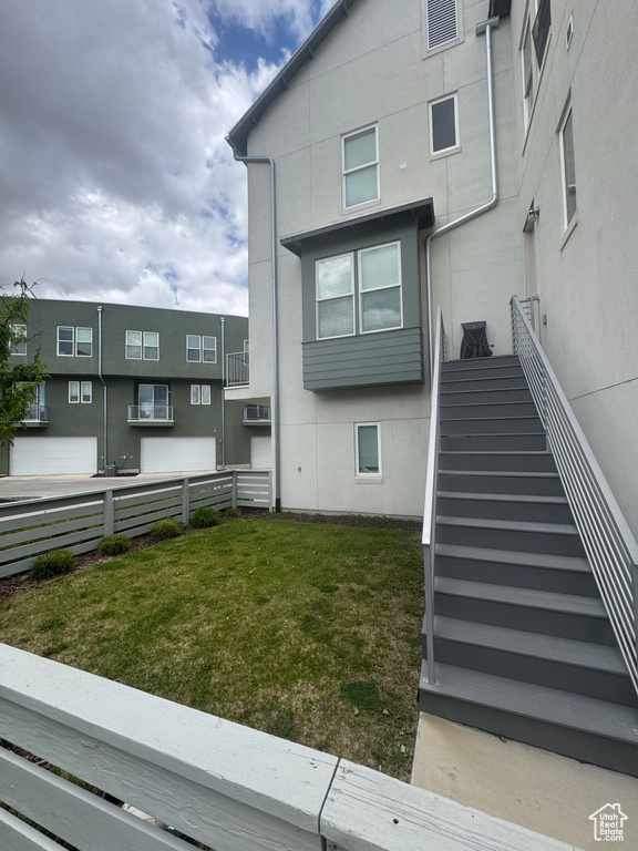 Back of property with fence, a wall mounted AC, stucco siding, and stairway