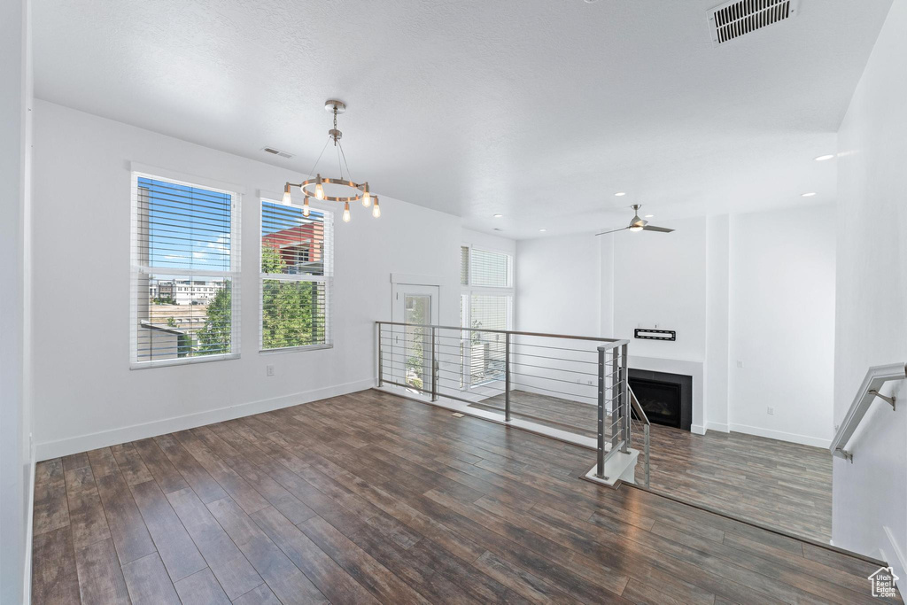 Unfurnished living room with wood finished floors, a chandelier, a ceiling fan, a fireplace, and recessed lighting