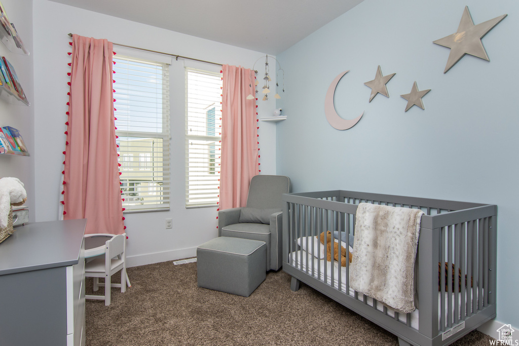Carpeted bedroom featuring a crib and baseboards