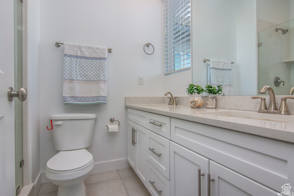 Full bathroom with toilet, baseboards, double vanity, tile patterned floors, and a shower