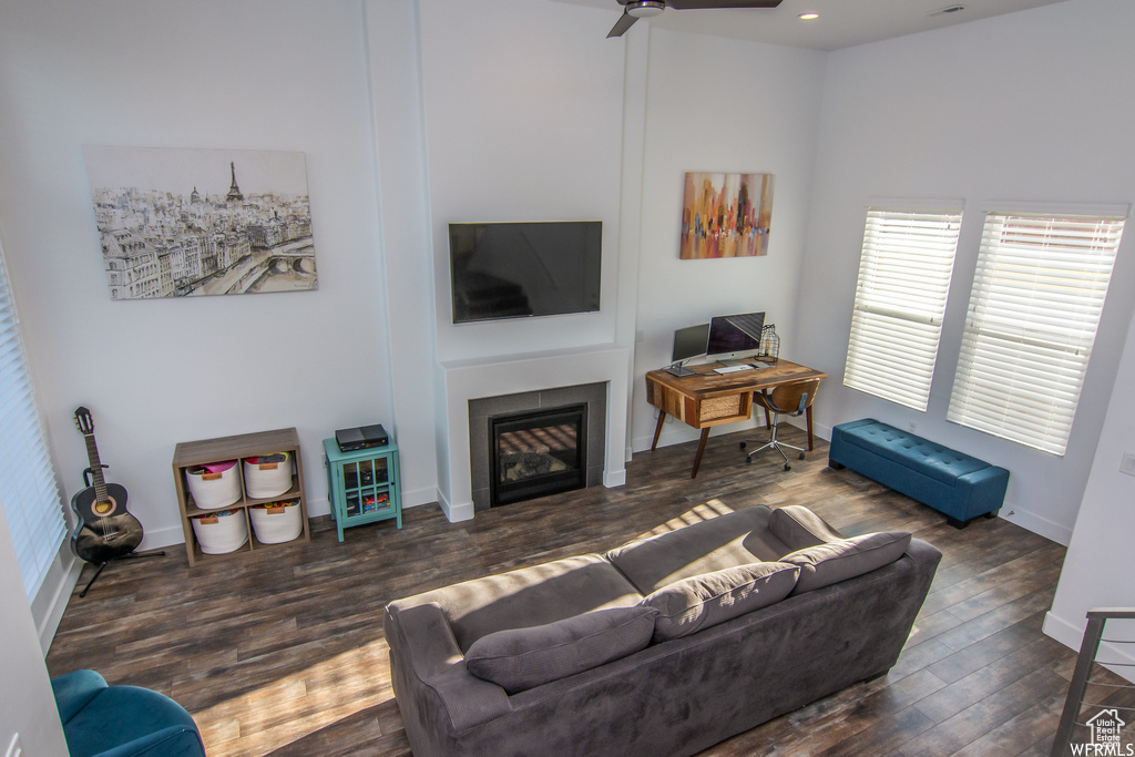 Living room with wood finished floors, a glass covered fireplace, baseboards, ceiling fan, and recessed lighting