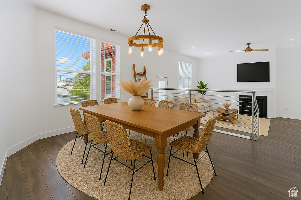 Dining area with dark wood-style floors, recessed lighting, a fireplace, ceiling fan, and a chandelier