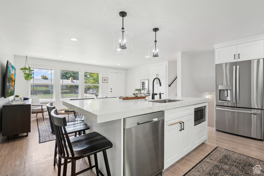Kitchen featuring appliances with stainless steel finishes, a sink, light countertops, white cabinetry, and recessed lighting