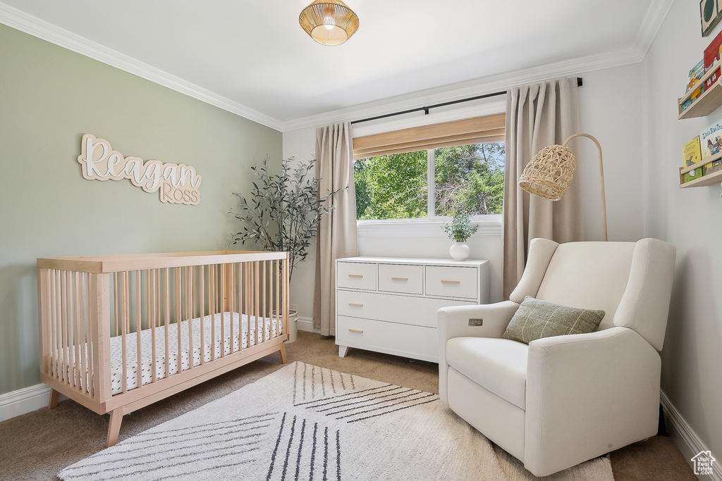 Bedroom featuring light carpet, crown molding, a crib, and baseboards