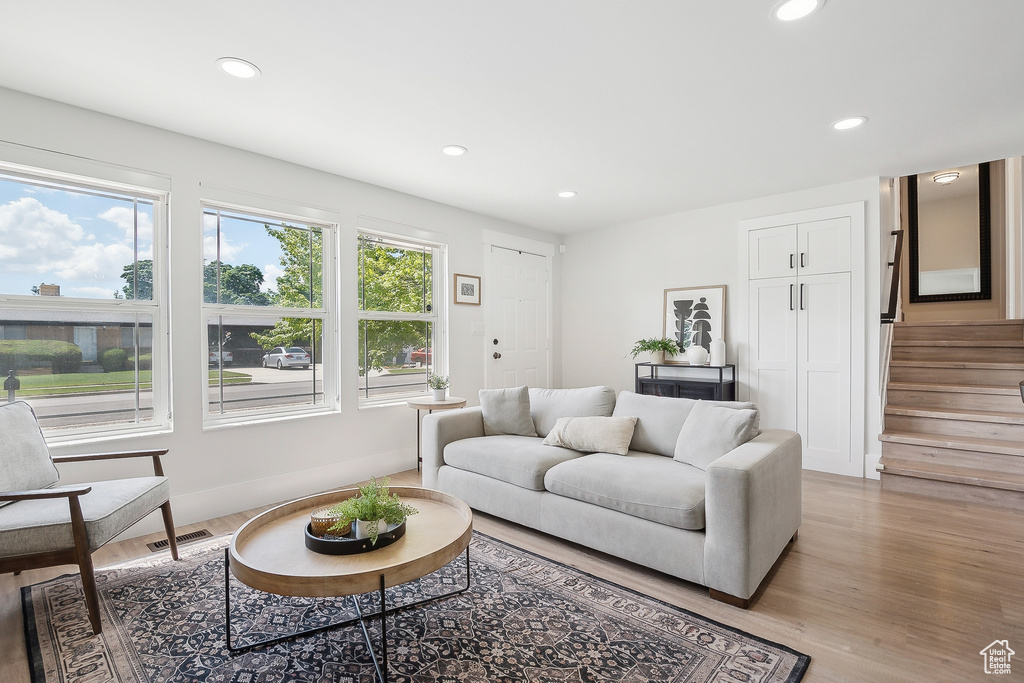 Living area with stairs, recessed lighting, and light wood-type flooring