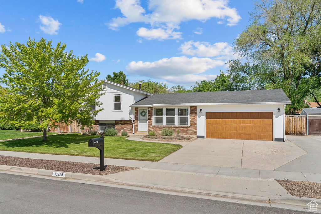 Split level home featuring a garage, concrete driveway, and brick siding