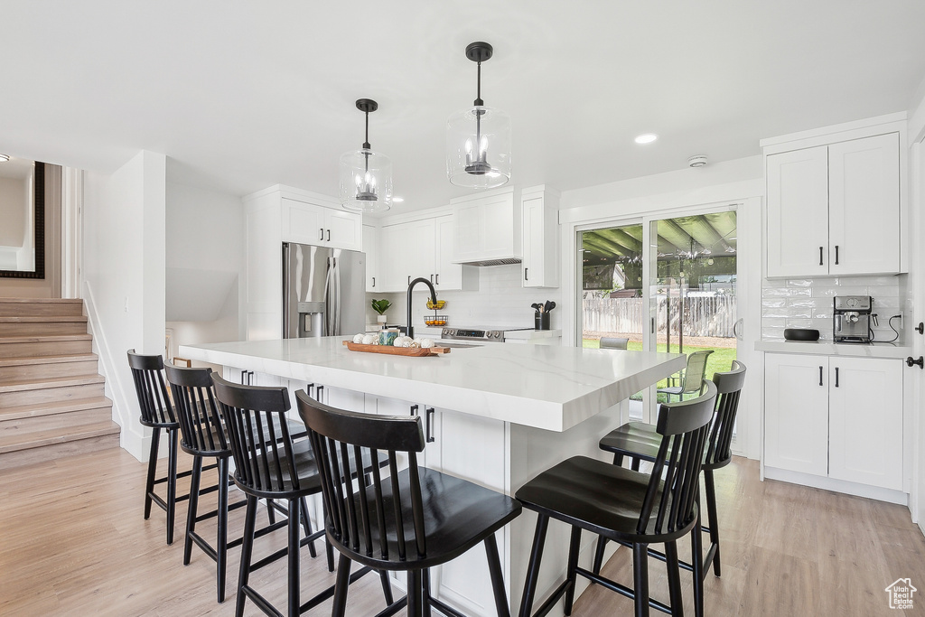 Kitchen with stainless steel fridge, backsplash, light wood finished floors, and recessed lighting