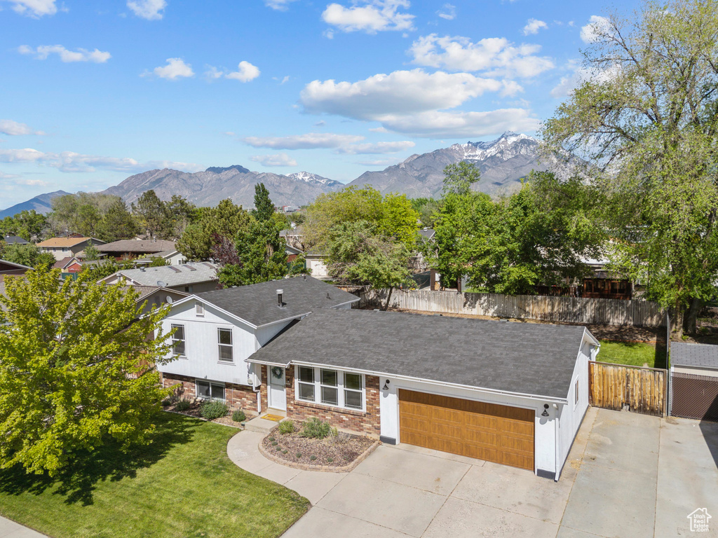 View of front facade featuring a garage, concrete driveway, a mountain view, and roof with shingles