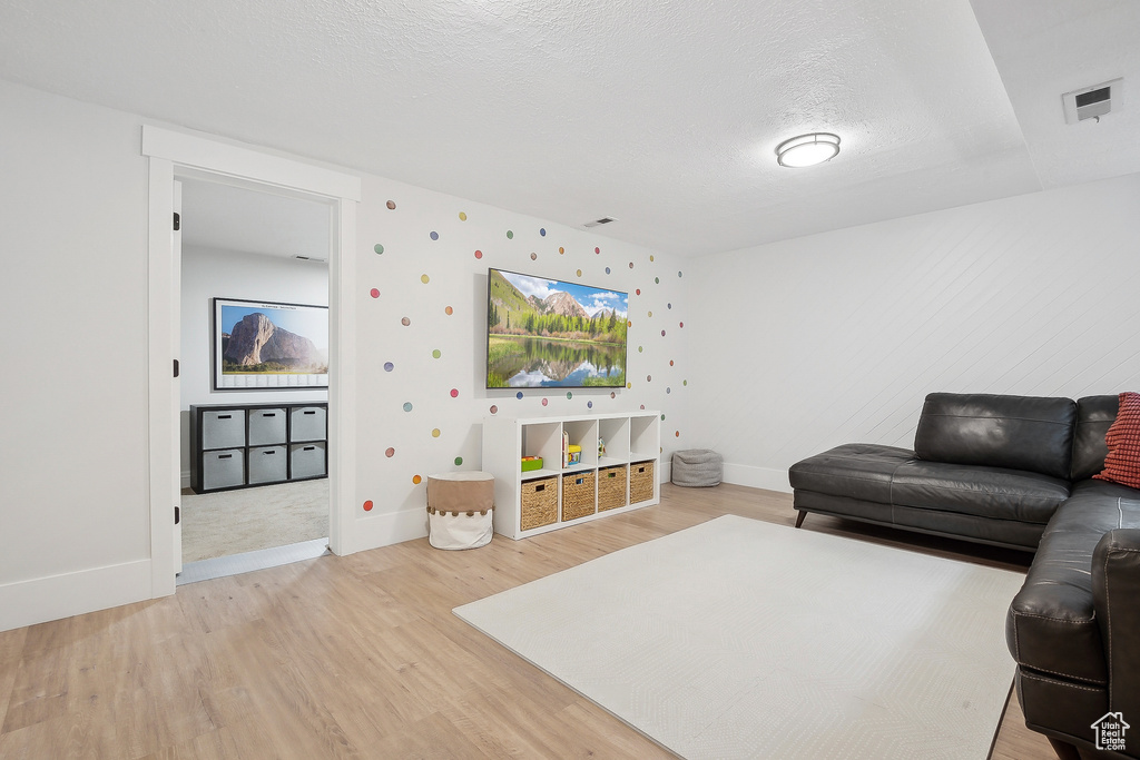 Living area featuring light wood-style floors, baseboards, and a textured ceiling