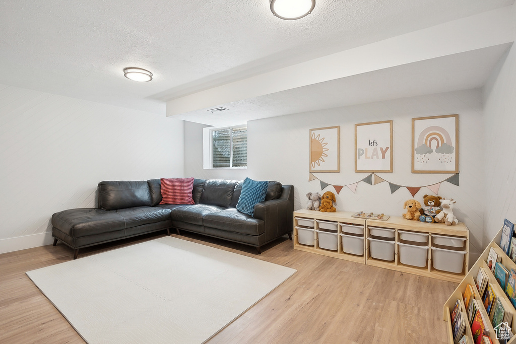 Living area with light wood finished floors, a textured ceiling, and baseboards