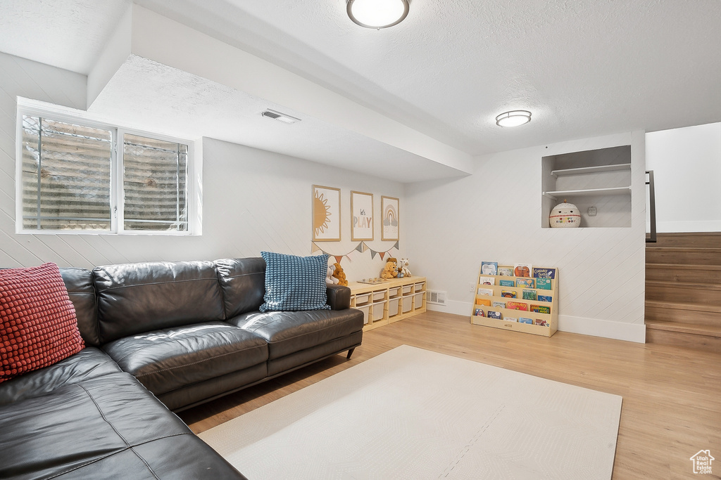 Living room with baseboards, wood finished floors, a textured ceiling, and built in shelves