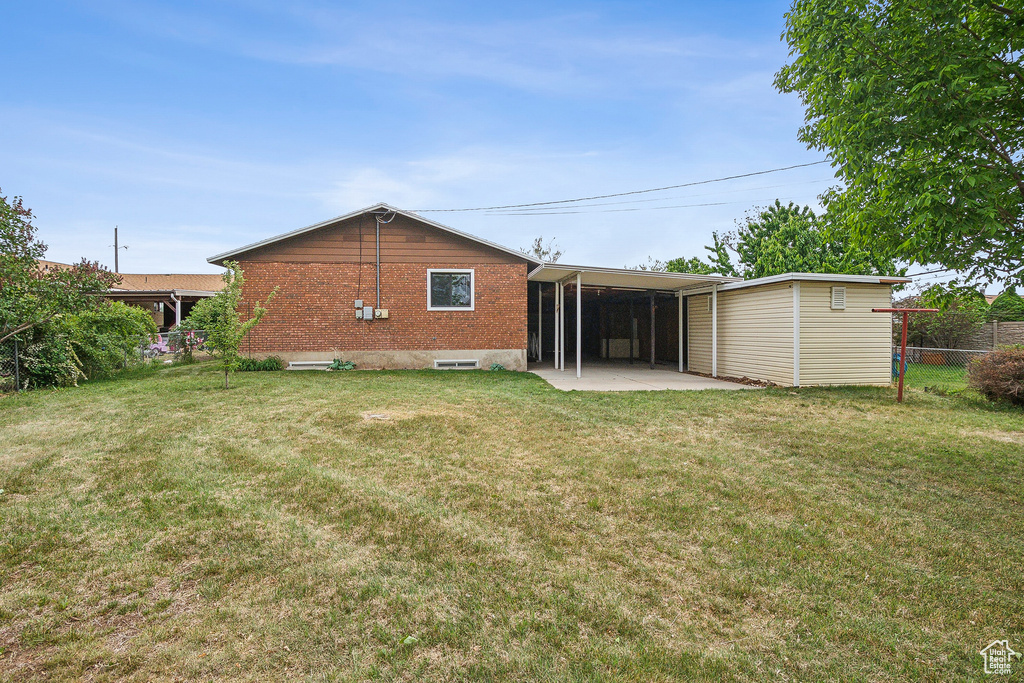 Back of property featuring brick siding, a patio area, and a carport
