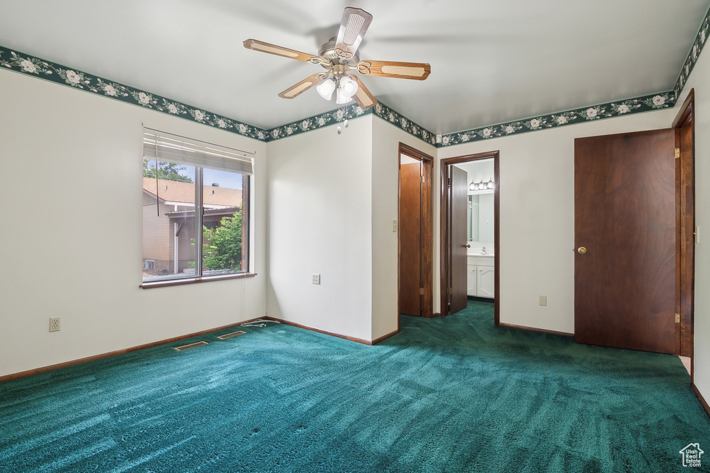 Unfurnished bedroom featuring carpet, baseboards, ensuite bathroom, and a ceiling fan