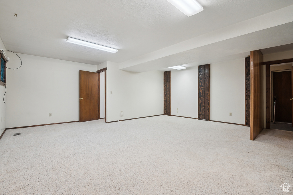 Finished basement with light colored carpet and baseboards