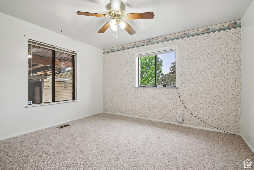Carpeted spare room with ceiling fan, baseboards, and wallpapered walls