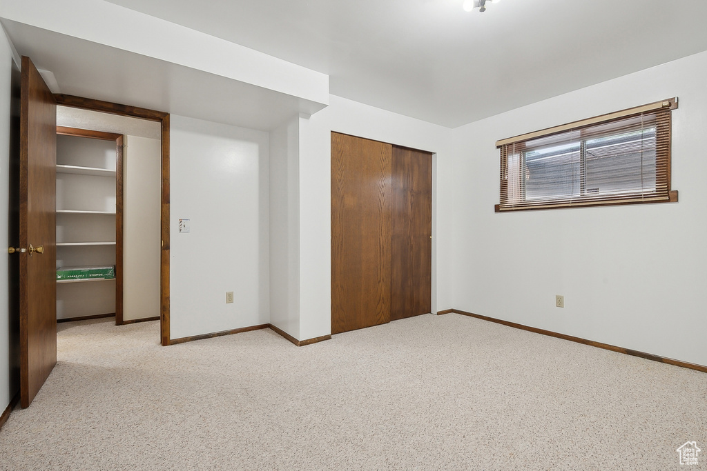 Unfurnished bedroom featuring light colored carpet, baseboards, and a closet