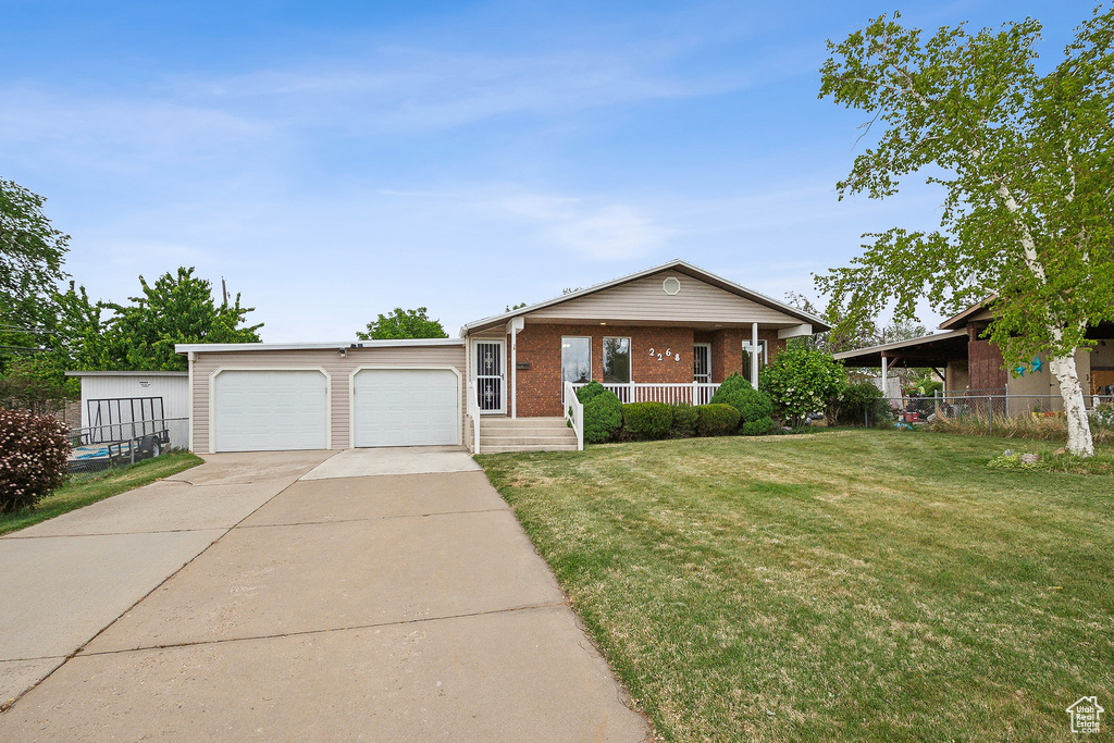 Ranch-style home with covered porch, brick siding, a front lawn, driveway, and an attached garage