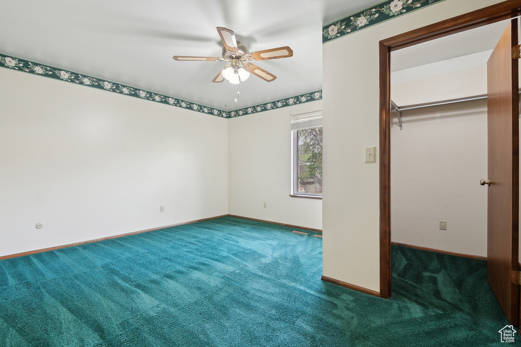 Unfurnished bedroom featuring a spacious closet, carpet, baseboards, a closet, and a ceiling fan