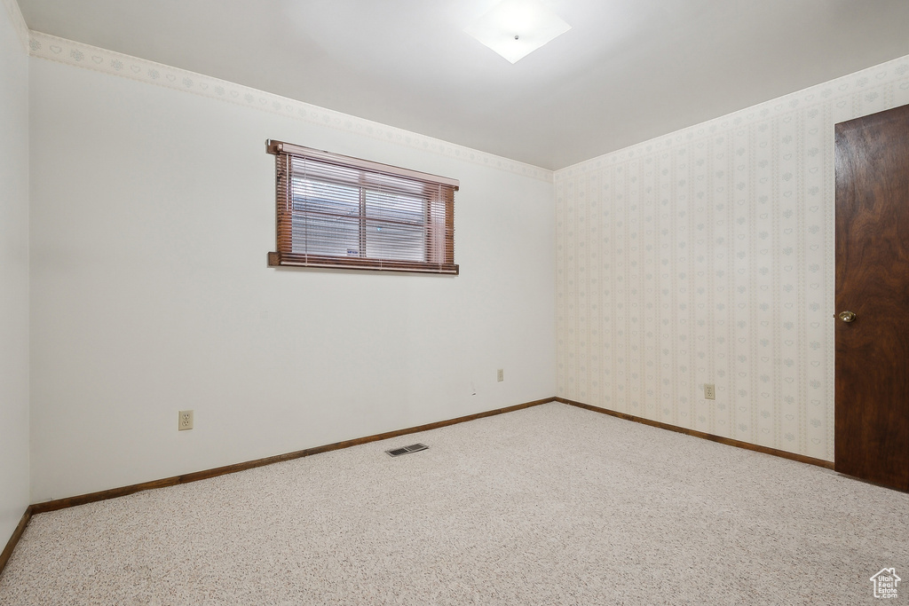 Carpeted empty room featuring baseboards and wallpapered walls