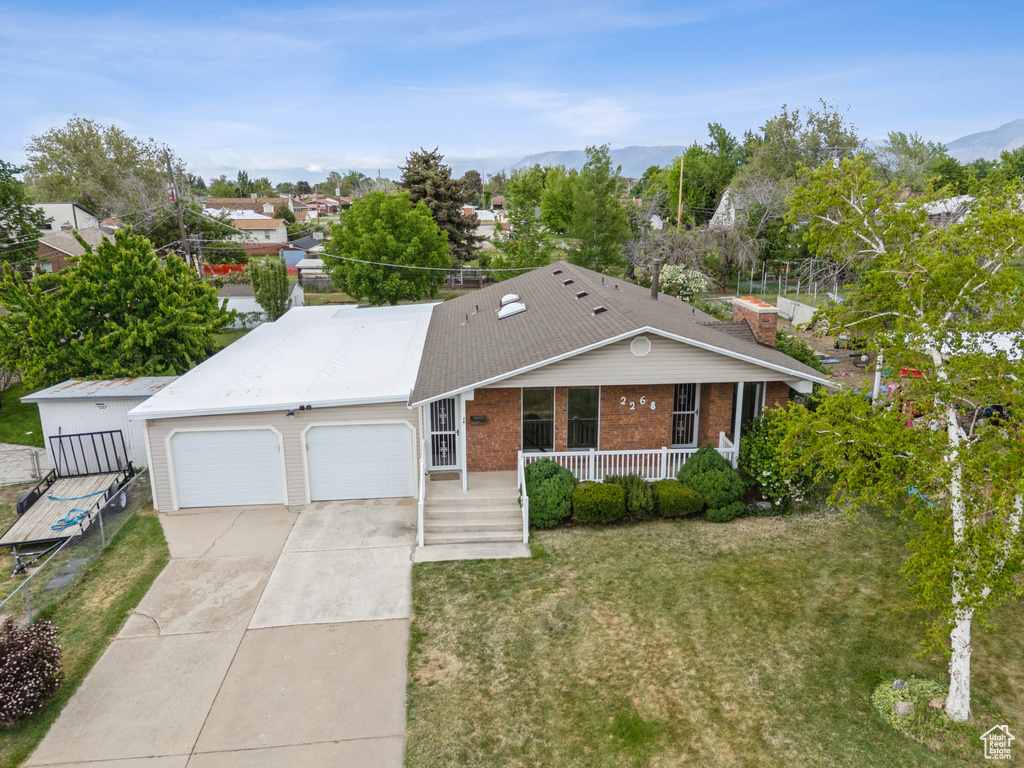 Ranch-style house featuring covered porch, an attached garage, brick siding, driveway, and a front lawn