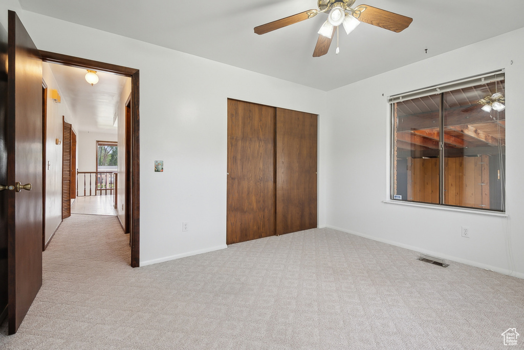 Unfurnished bedroom with carpet flooring, a closet, baseboards, and a ceiling fan