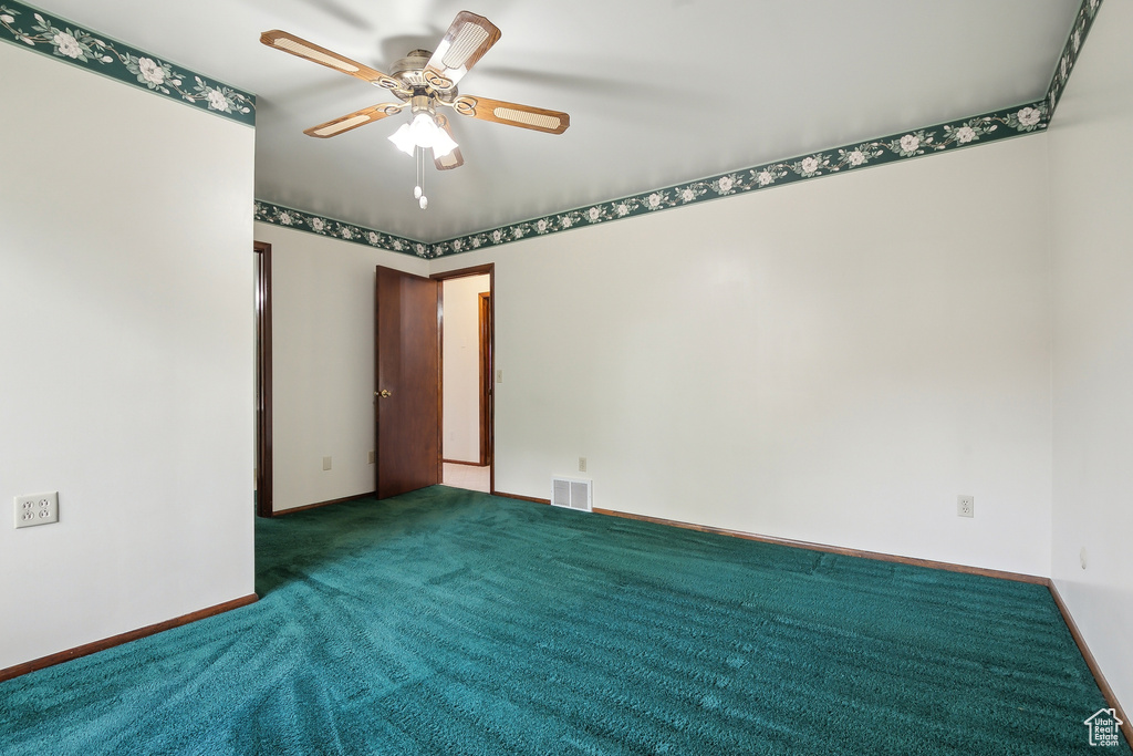 Carpeted spare room featuring ceiling fan and baseboards