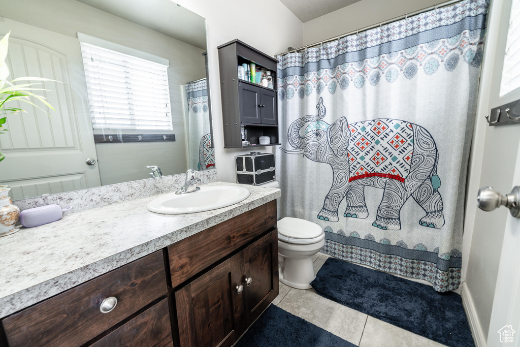 Full bathroom featuring tile patterned floors, vanity, toilet, and a shower with shower curtain