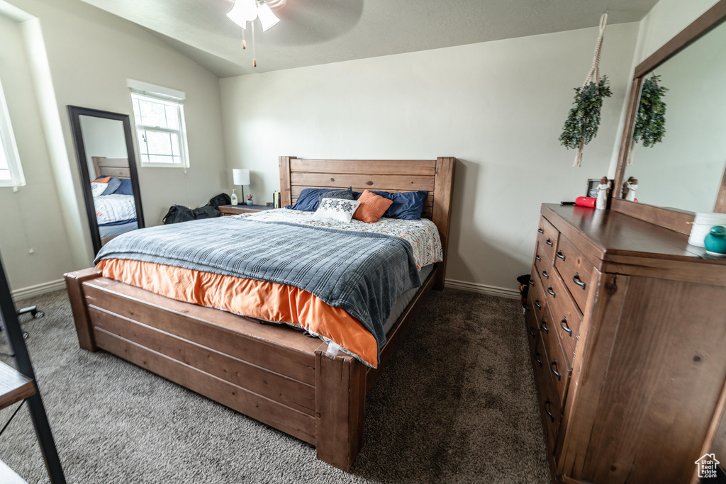 Bedroom featuring dark carpet, lofted ceiling, baseboards, and a ceiling fan