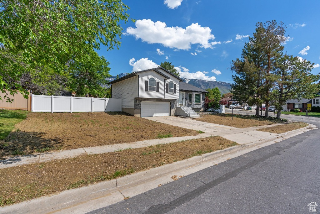 Split level home with driveway, a garage, fence, and a mountain view