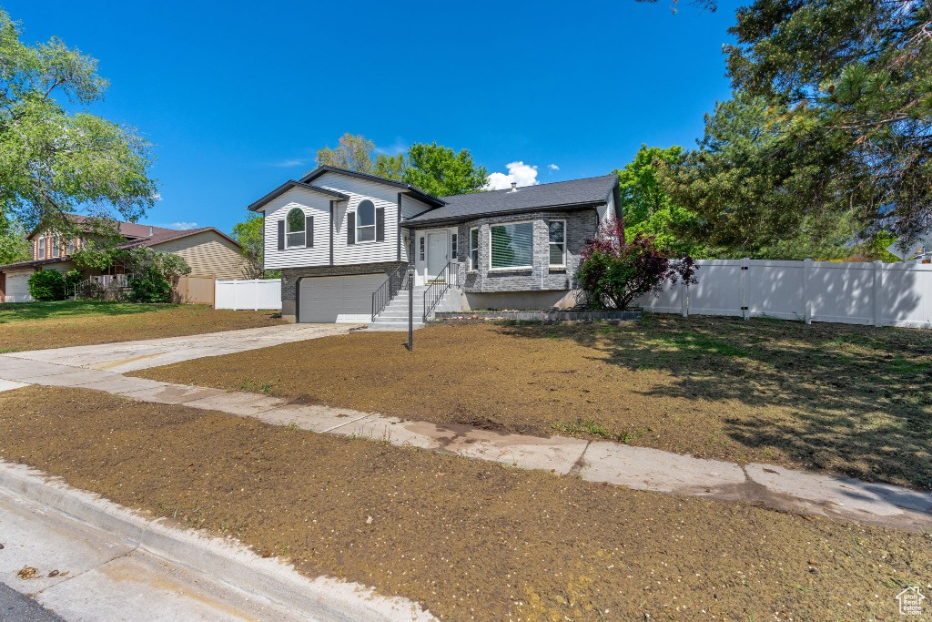 Tri-level home with driveway, fence, and an attached garage