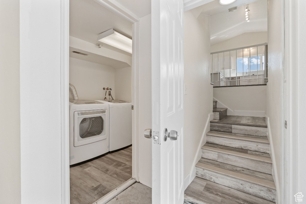 Clothes washing area featuring washer and dryer and wood finished floors