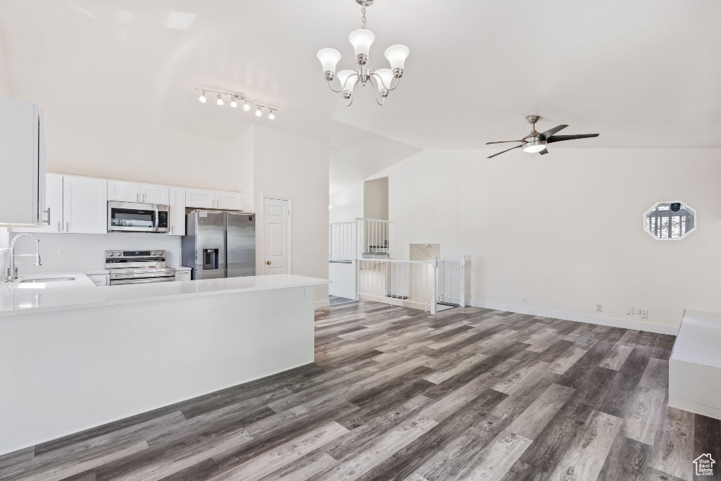 Kitchen featuring stainless steel appliances, a sink, high vaulted ceiling, light countertops, and wood finished floors