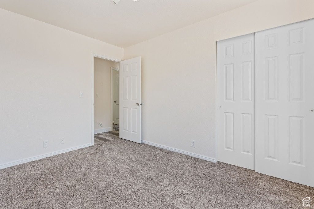 Unfurnished bedroom with carpet flooring, a closet, and baseboards