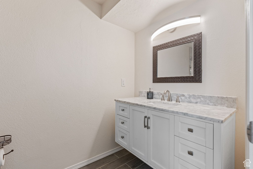 Bathroom with vanity, wood finished floors, and baseboards