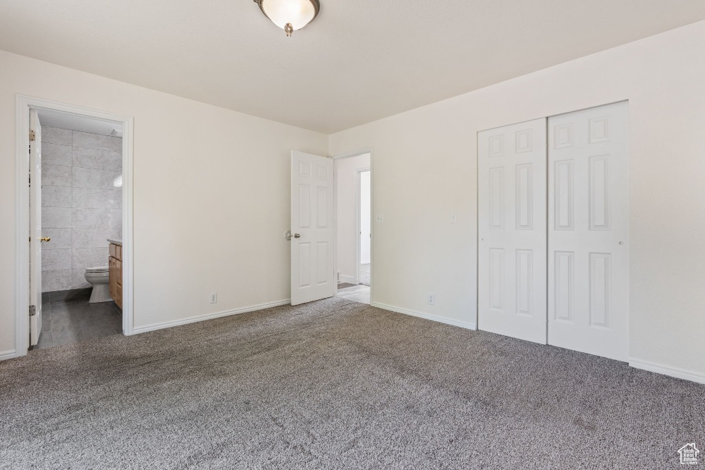 Unfurnished bedroom featuring carpet floors, a closet, baseboards, and ensuite bath