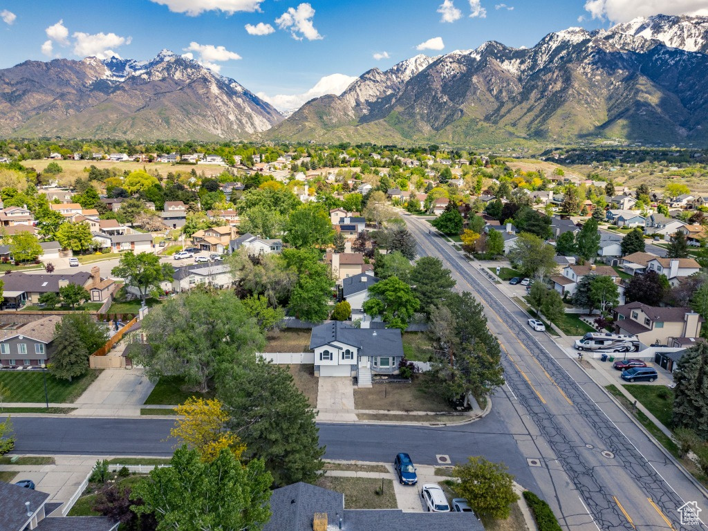 Aerial view of property and surrounding area featuring a mountainous background and nearby suburban area
