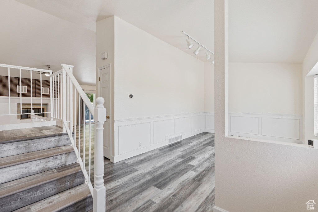 Stairway with wood finished floors, a wainscoted wall, and a decorative wall