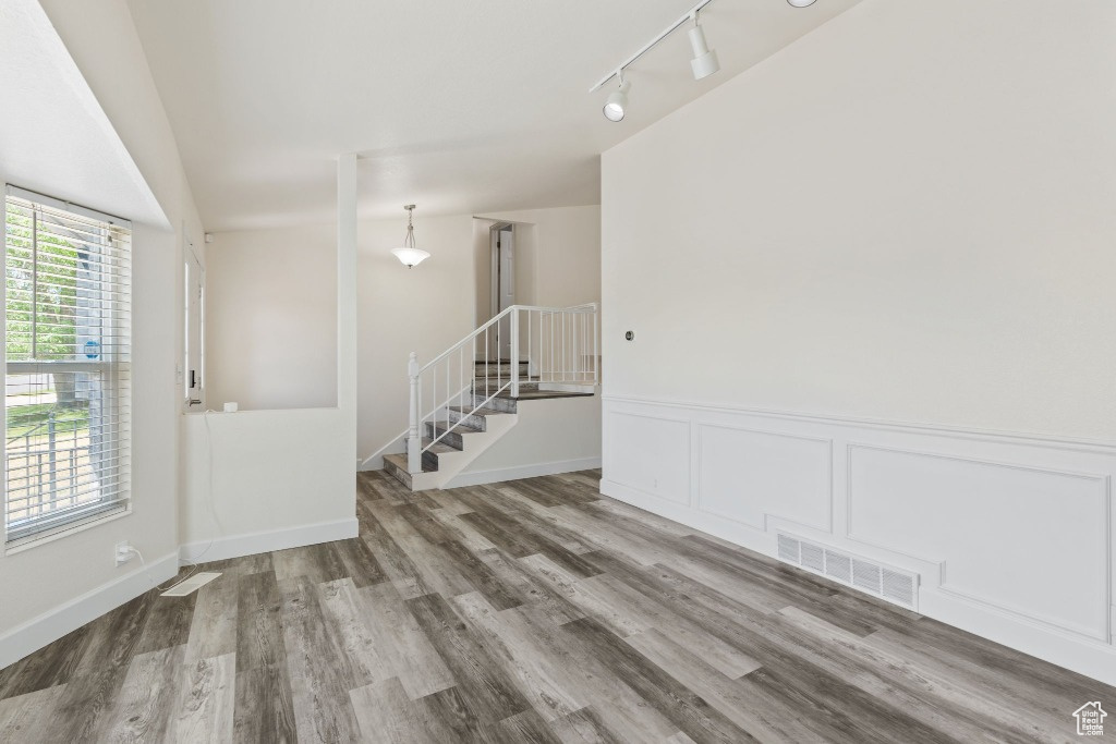Unfurnished room with wood finished floors, rail lighting, and a wainscoted wall
