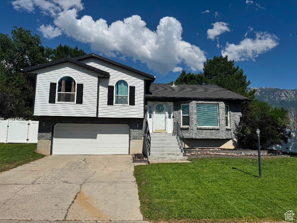 Tri-level home with concrete driveway, a garage, and a gate