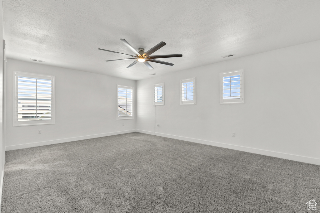 Carpeted spare room with baseboards, ceiling fan, and a textured ceiling