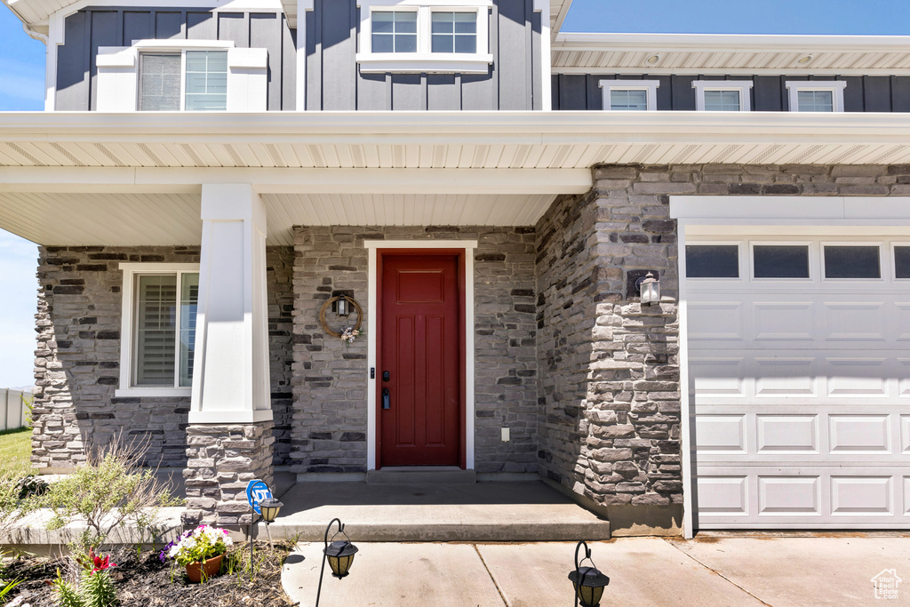 Entrance to property with board and batten siding, a garage, and stone siding
