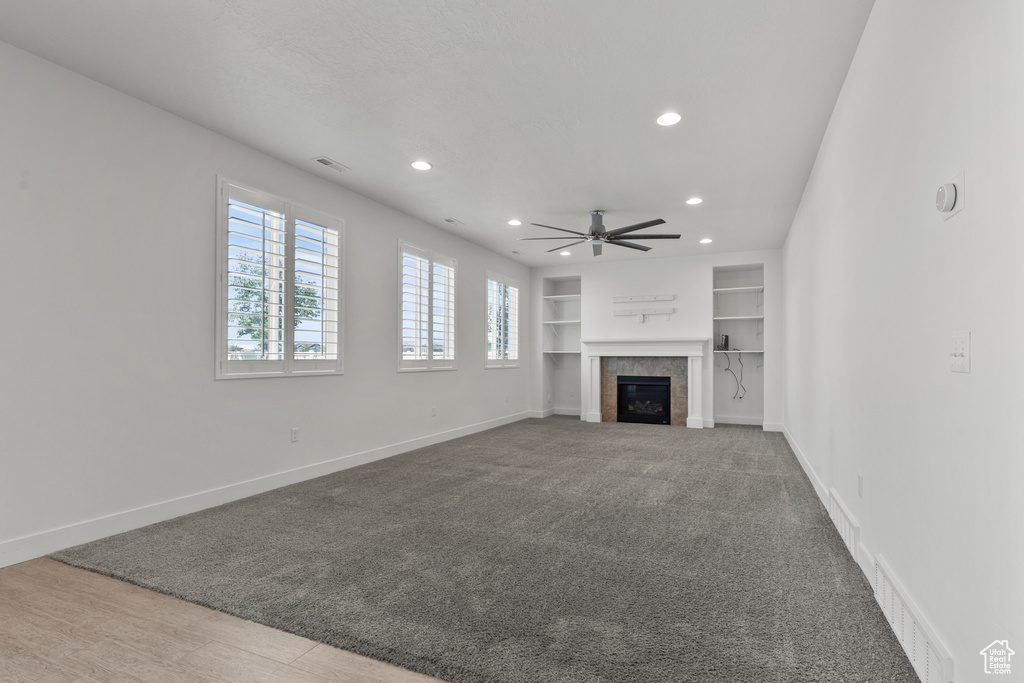 Unfurnished living room featuring recessed lighting, ceiling fan, built in features, baseboards, and a tiled fireplace