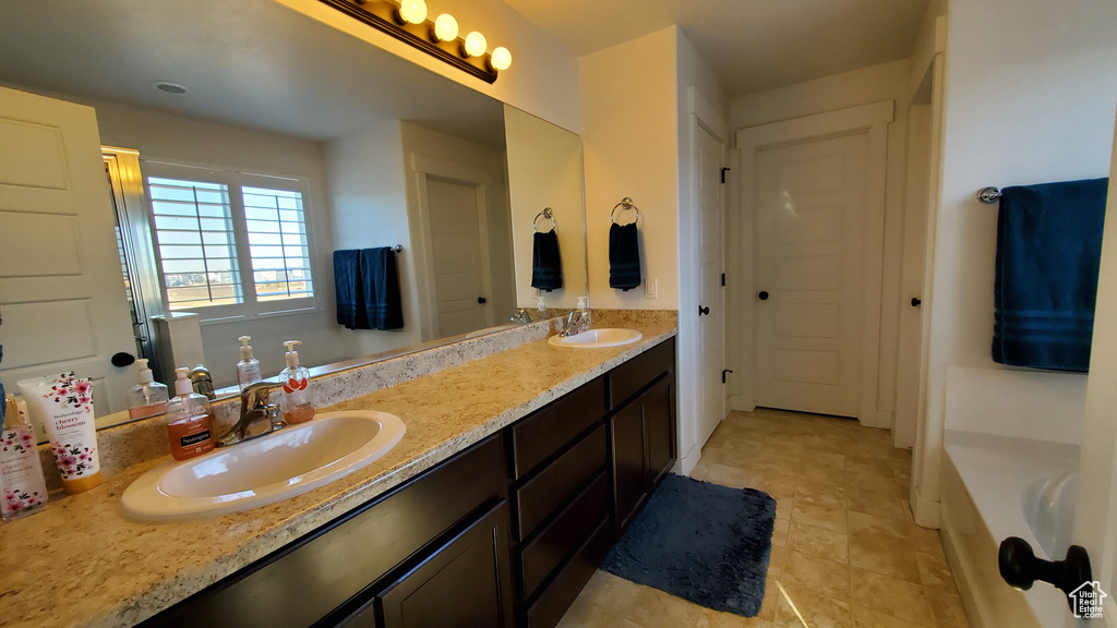 Bathroom with double vanity, a tub, and tile patterned flooring