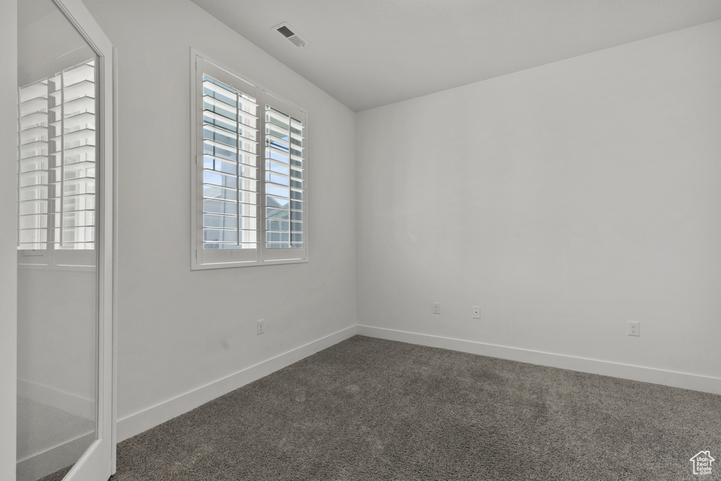 Empty room featuring dark carpet and baseboards